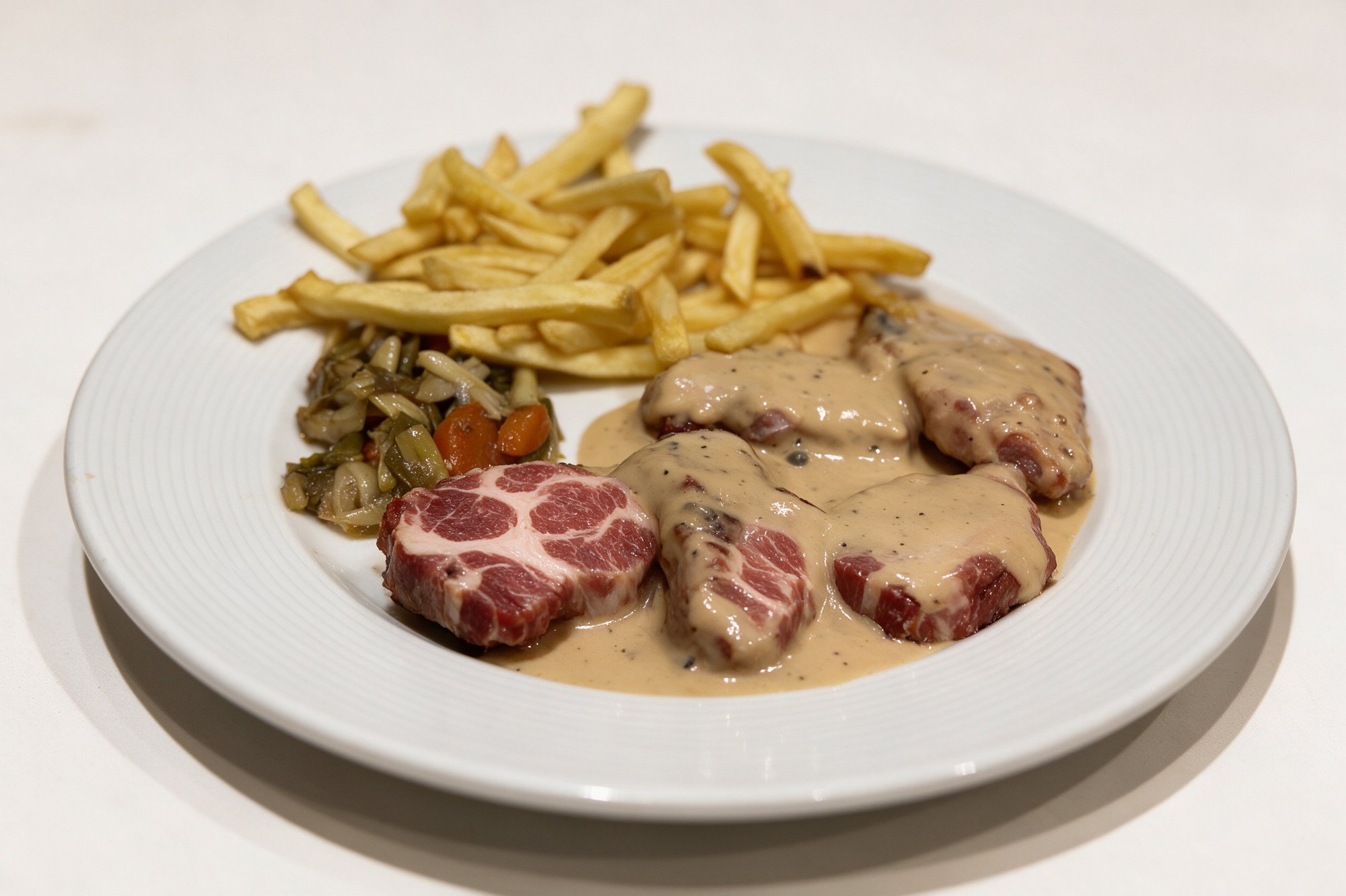Secreto con Salsa de Pimienta de Restaurante Pippo, salsa densa y brillante sobre carne y patatas